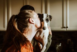 Woman kissing dog that man is holding
