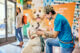 Dogtopia employee in Dogtopia location lobby petting white dog with dog's female owner in background leaving the facility