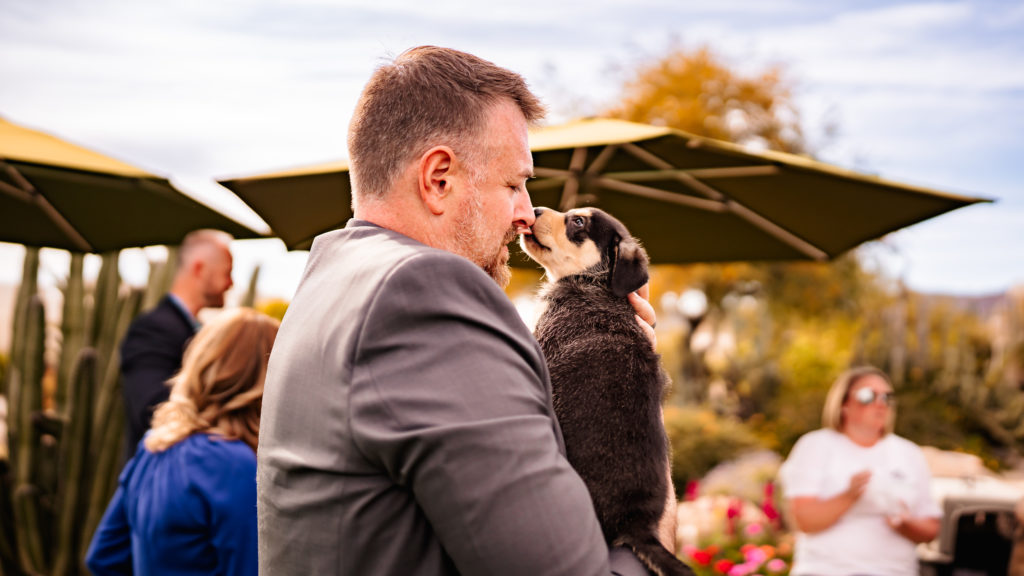 Man holding small dog that is licking his nose