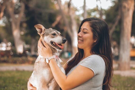 Female pet owner petting dog outside