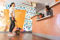 Pet parent inside Dogtopia lobby with dog on leash speaking with Dogtopia employee at a desk