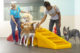 Two Canine Coaches petting a group of dogs inside a Dogtopia playroom.