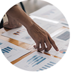 Hand pointing to papers on a desk with data on them