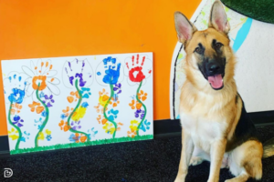 Dogtopia dog beside paw-painted art